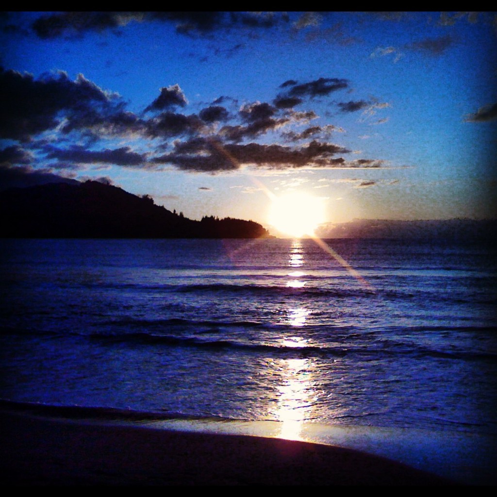 A sunset over the ocean with clouds in the sky.