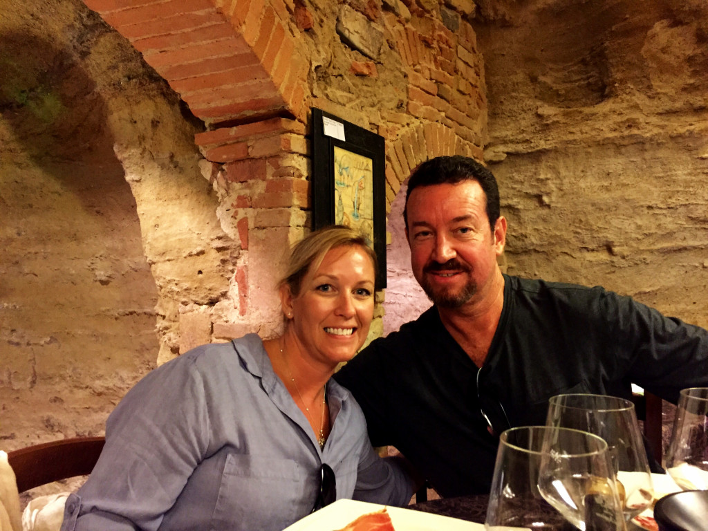 A man and woman sitting at a table with wine glasses.